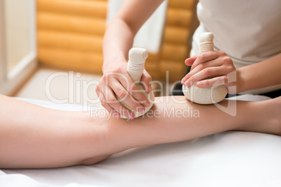Masseuse doing thai massage with salt bags