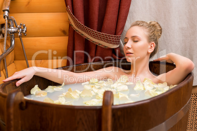 Girl relaxing in bath with oils and rose petals