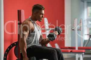 Handsome man training with dumbbells in gym