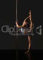 Pole dance. Flexible girl doing vertical split