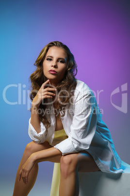 Brunette dressed in white shirt sitting on cube