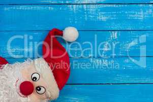 Smiling Christmas Santa Claus in a red cap on blue wooden surfac