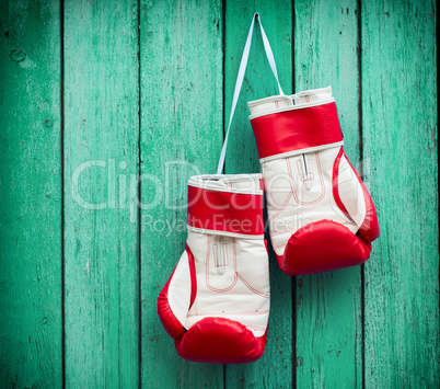 pair of red boxing gloves hanging on a nail on a background of g