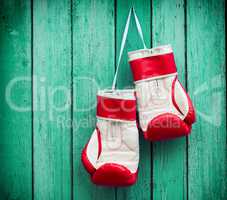 pair of red boxing gloves hanging on a nail on a background of g