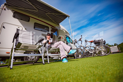 Woman sitting on a chair near the camper and looking at a laptop