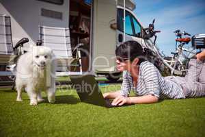 Woman on the grass with a dog looking at a laptop