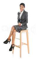 Black businesswoman seated on chair.