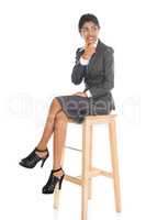 Black business woman seated on chair.