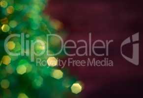 Blurred Christmas tree with garland, green bokeh on a dark red b
