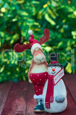 Christmas reindeer with snowman toy on blurred green background