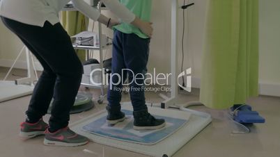 At the medical clinic Evexia on a robotic system analysis and training balance doctor trains a little boy to keep the balance