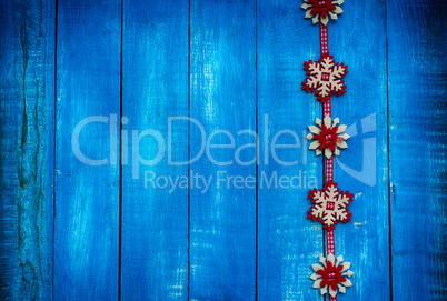 Ribbon with felt snowflakes on a blue wooden surface, copy space
