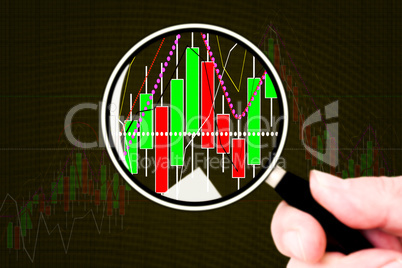 Hand holding magnifying glass in front of chart