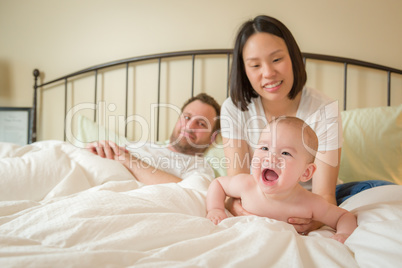 Chinese and Caucasian Baby Boy Laying In Bed with His Parents