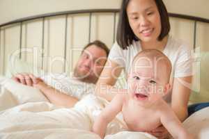 Chinese and Caucasian Baby Boy Laying In Bed with His Parents
