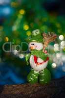 Snowman with a broom on a background of blurred Christmas tree
