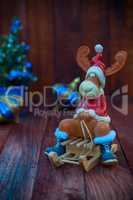 Toy Christmas reindeer in Christmas clothes sitting on a wooden