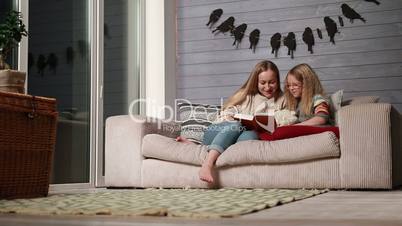 Young mother reading a book to her cute daughter