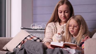 Mother and daughter reading bedtime story on sofa