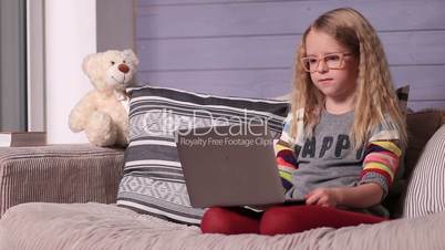 Smiling little girl with laptop computer at home