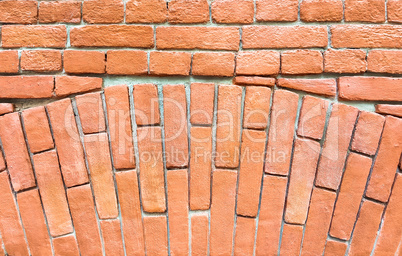Fragment of a red brick wall with an arch.