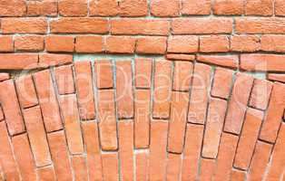 Fragment of a red brick wall with an arch.