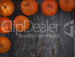 Orange mandarins on the gray old wooden surface, top view