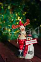 elk and snowman with a greeting sign merry christmas on a wooden