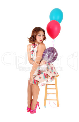 Happy woman sitting with balloons.