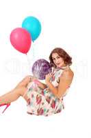 Woman sitting on floor with balloons.