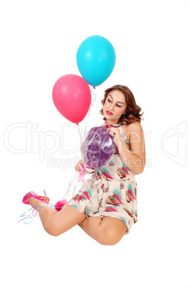 Woman kneeling on floor with balloons.