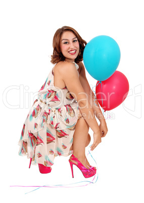Woman crouching on floor with balloons.