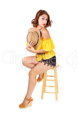 Woman sitting in shorts and hat.