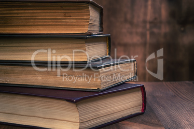 stack of old books on a brown wooden background