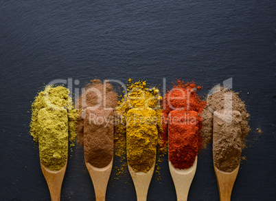 colorful herbs and spices in wooden spoons
