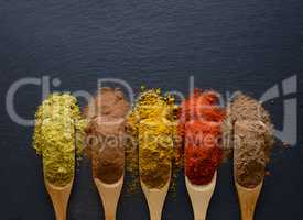 colorful herbs and spices in wooden spoons
