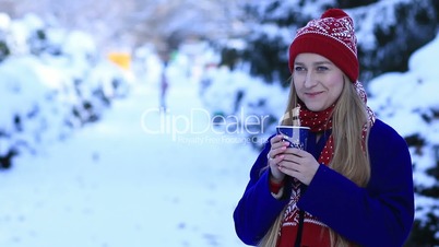 Smiling young woman drinking coffee in cold winter