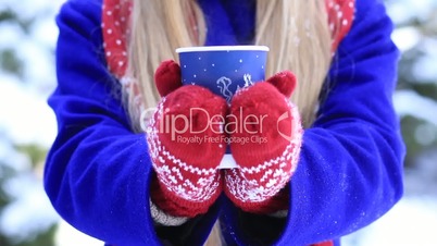 Female hands with hot drink outdoors on winter day