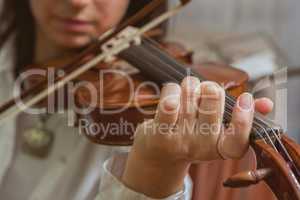 Symphony orchestra on stage, hands playing violin. Shallow depth