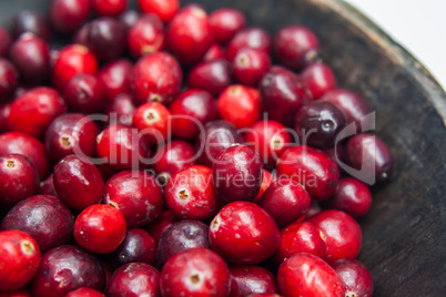 Fresh cranberries fruits in rustic wooden bowl in daylight