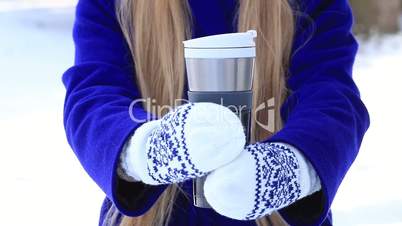 Female hands with thermal coffee mug in winter day