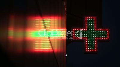 Illuminated green and red pharmacy sign at night