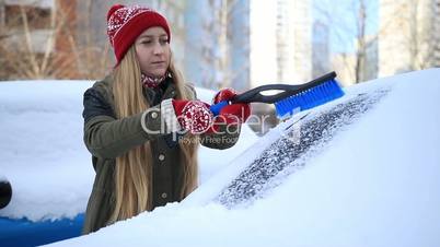 Woman removing snow from car windshield