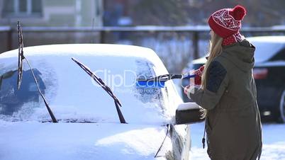 Lady removing snow from windshield with snow brush