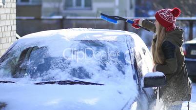 Woman cleaning snow from car roof using brush