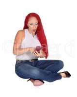 Woman sitting on floor with cellphone.