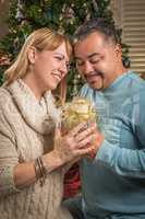 Young Mixed Race Couple with Present Near Christmas Tree