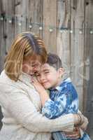 Mother and Mixed Race Son Hug Near Fence