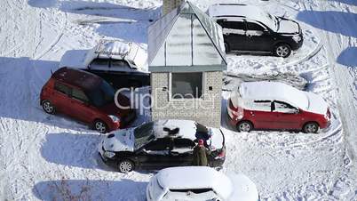 Woman brushing snow from car with snow brush