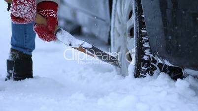 Close up of woman shoveling snow from car